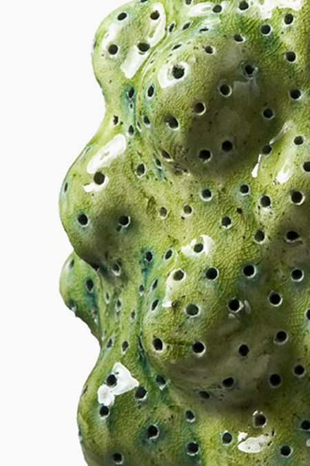 A green Danish ceramic sculpture with holes in it.