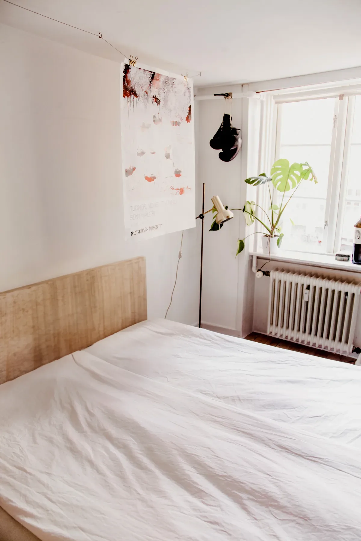A white bed in a room with a window.