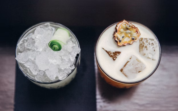 Two drinks with ice and ice cubes on a table.
