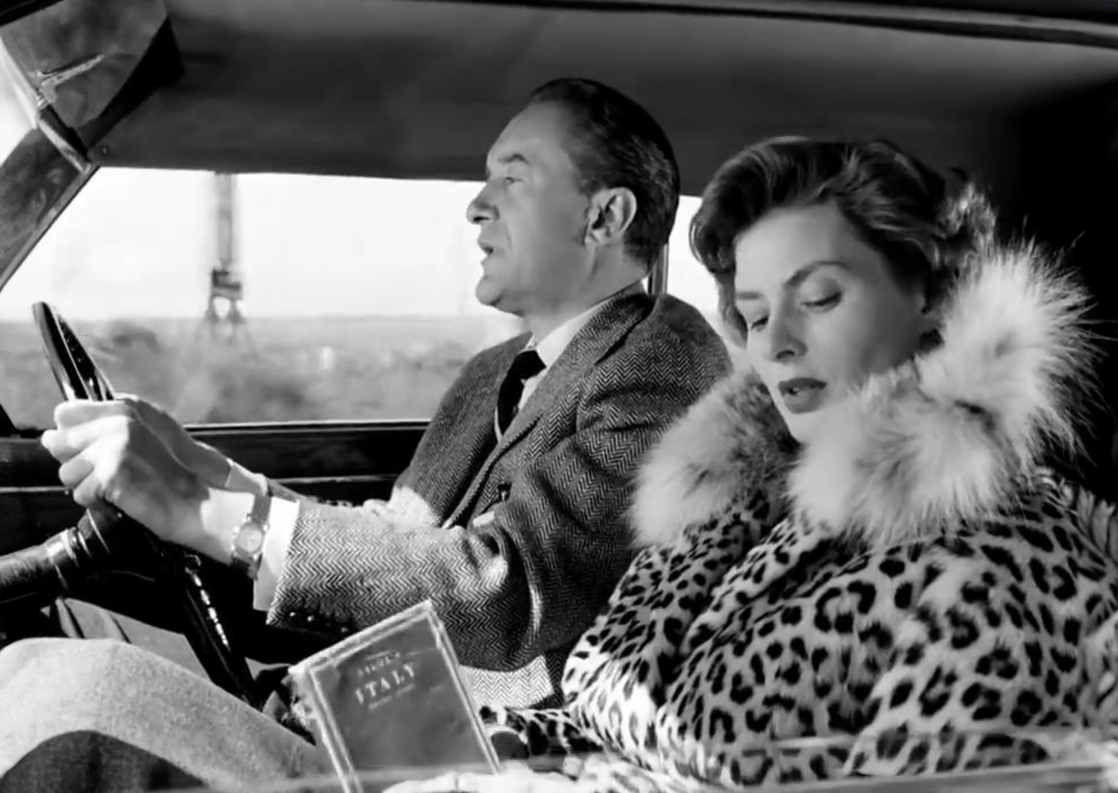 A man and woman, reminiscent of Ingrid Bergman's classic elegance, sit in a car.