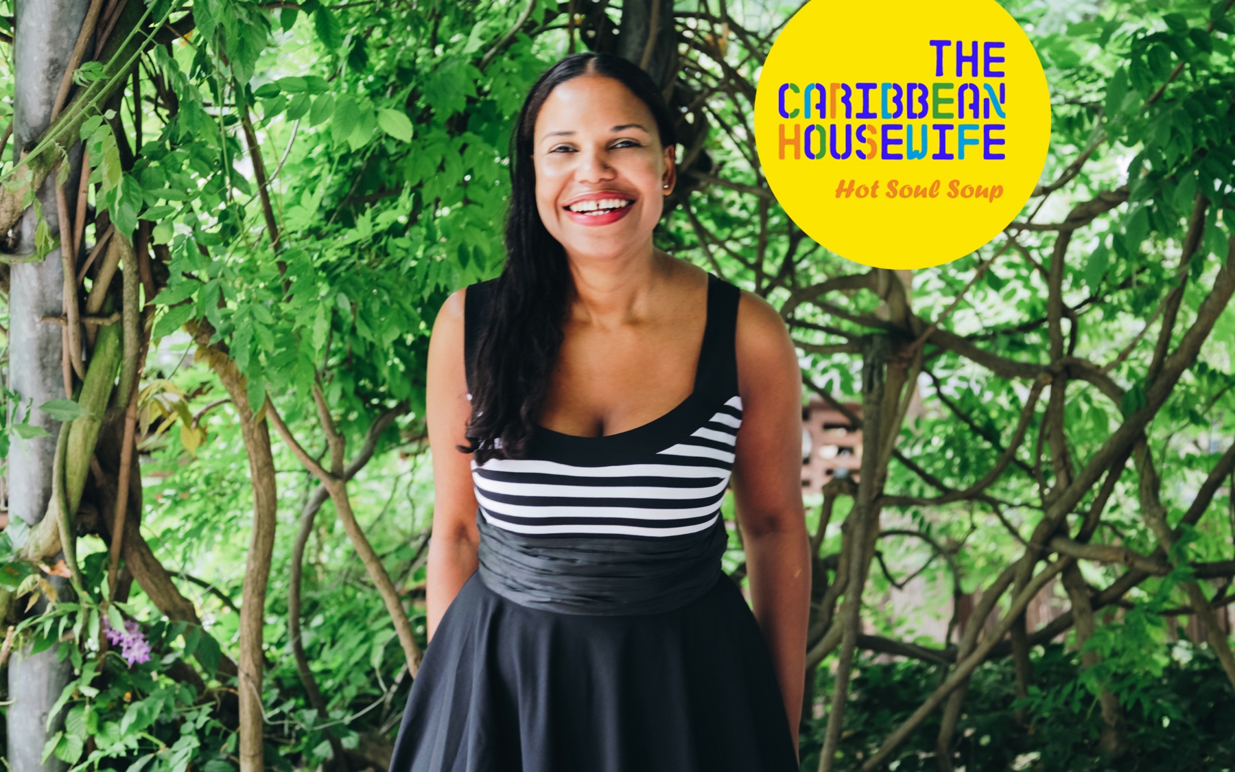 A woman in a black and white dress standing in front of a tree.