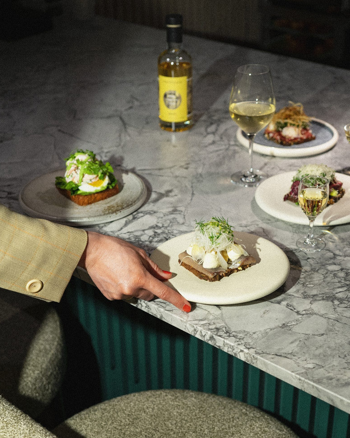 Four plates of food on a table in front of a person at Copenhagen restaurants.