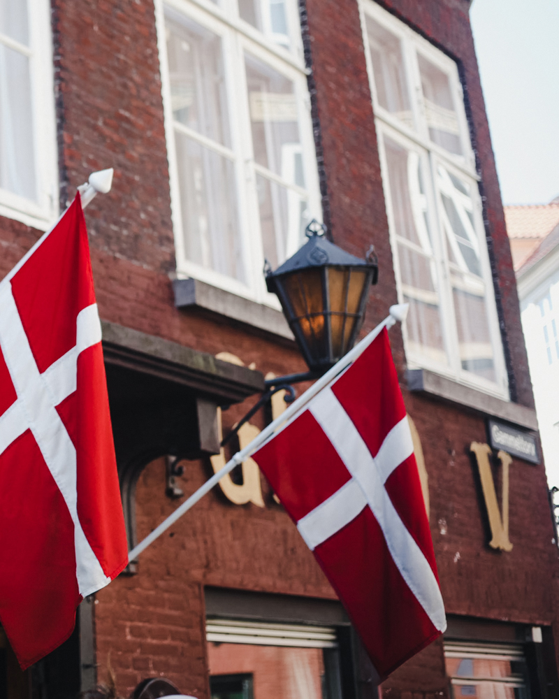 Two Danish flags hanging outside of a Copenhagen restaurant.