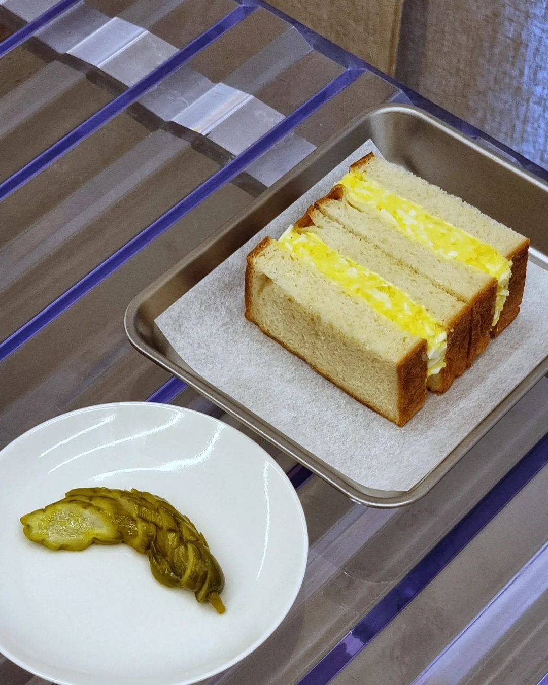 A piece of cake and a pickle served on a tray at a Copenhagen restaurant.