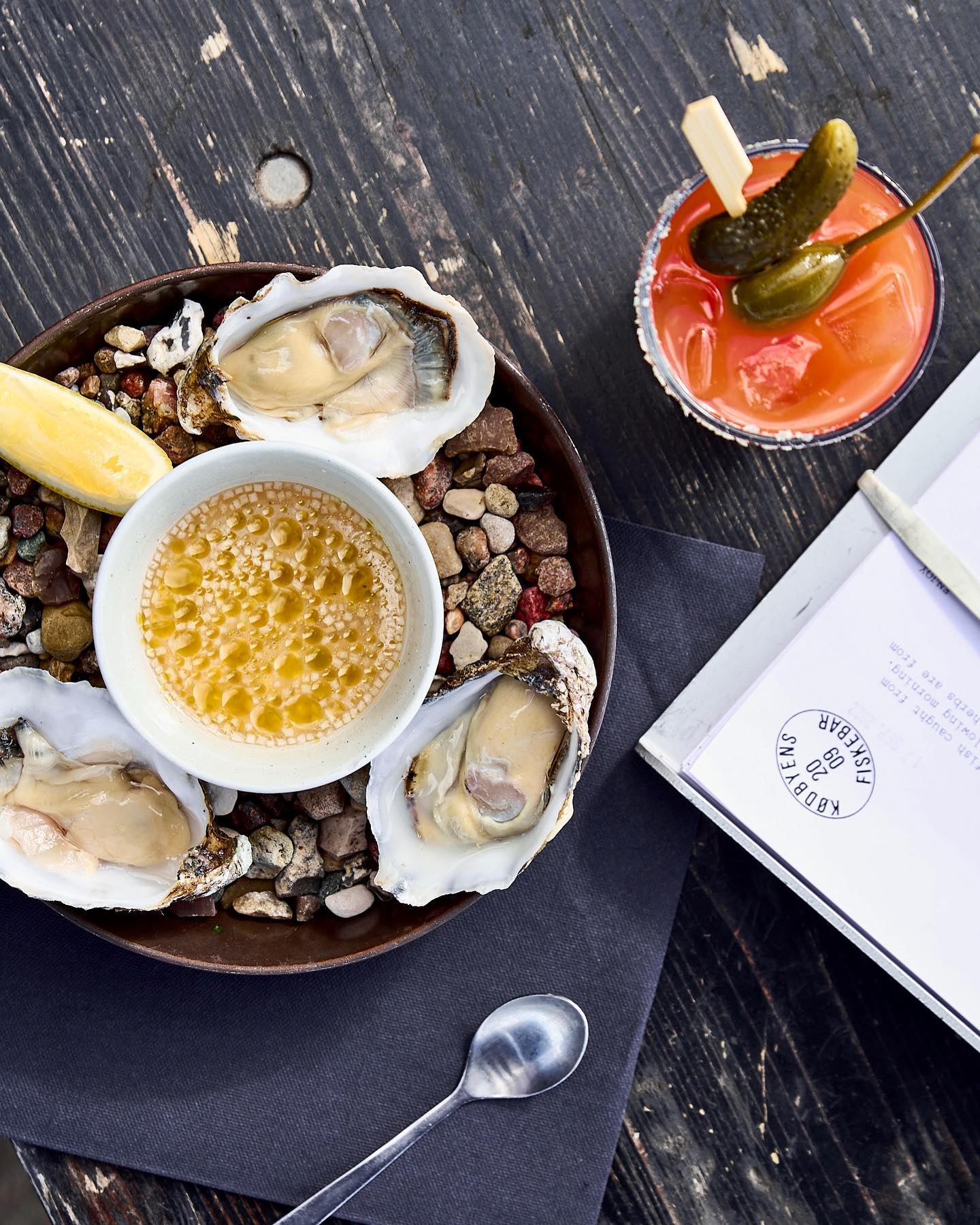 A plate of oysters and a book on a table at Copenhagen restaurants.