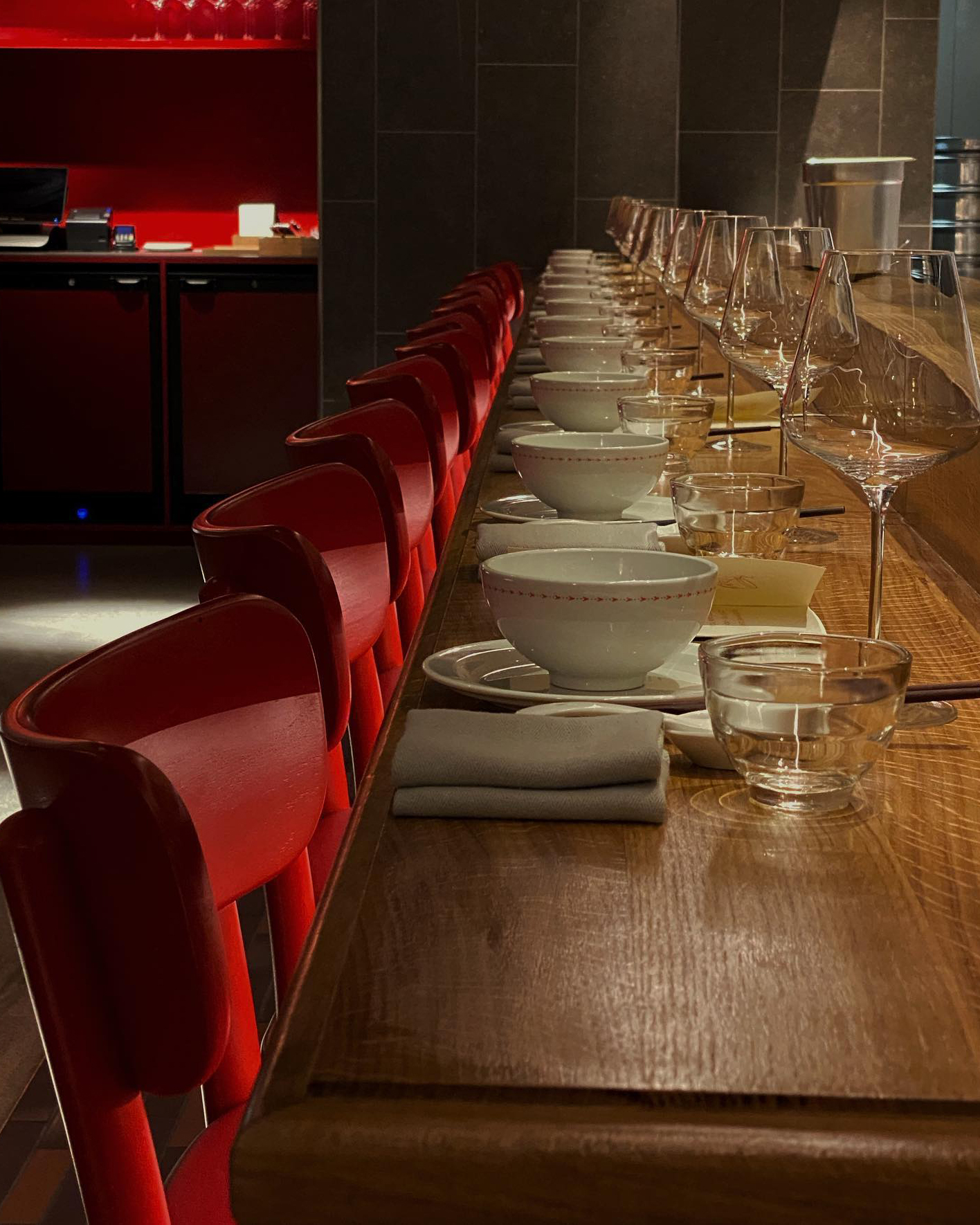 A long bar with red chairs and wine glasses at a Copenhagen restaurant.