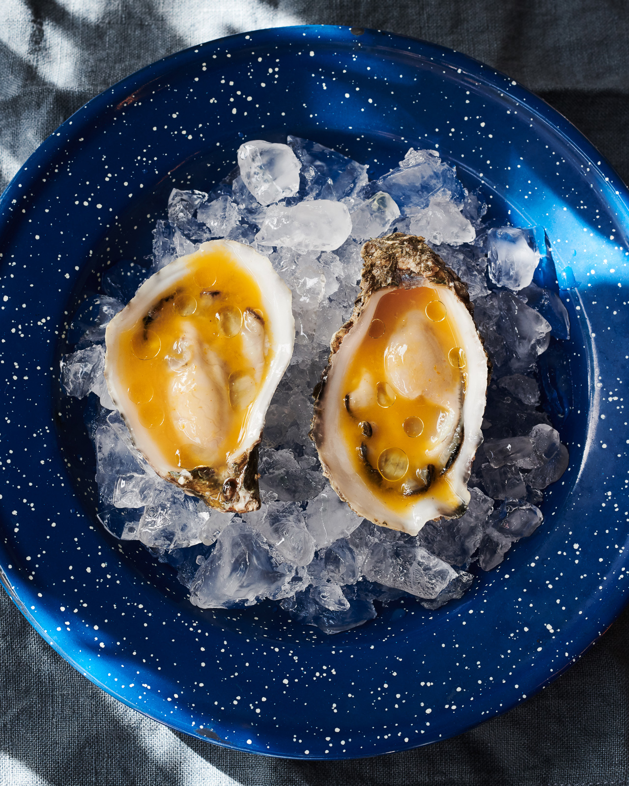 Two oysters on ice on a blue plate at Copenhagen restaurants.