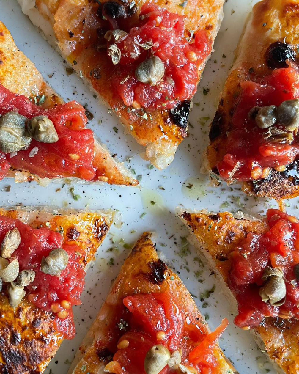 A plate of pizza with tomatoes and peppers at Copenhagen restaurants.