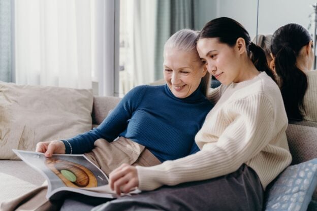 A mother and adult daughter sharing a warm moment on a couch, a representative image, not a photograph of any person discussed in the article.
