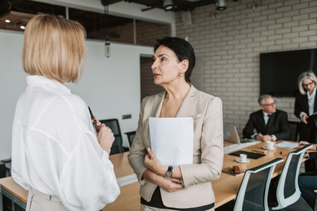 A representative image of two colleagues in a professional conversation, not a photograph of any person discussed in the article.