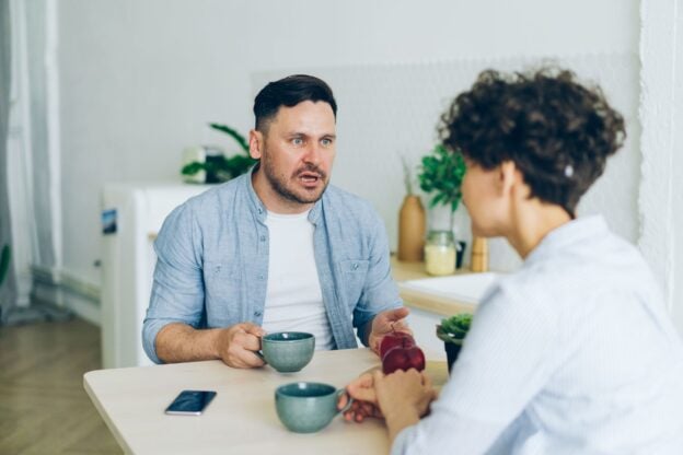A representative image of a couple talking at a table, not a photograph of any person discussed in the article.