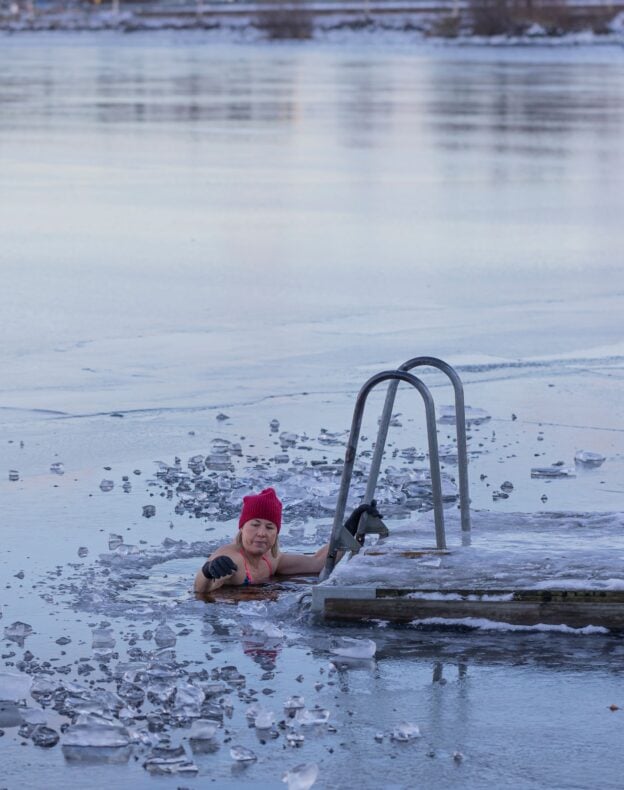 A woman swimming amidst ice in a frozen lake, holding onto a ladder, a representative image and not a photograph of any person discussed in the article.