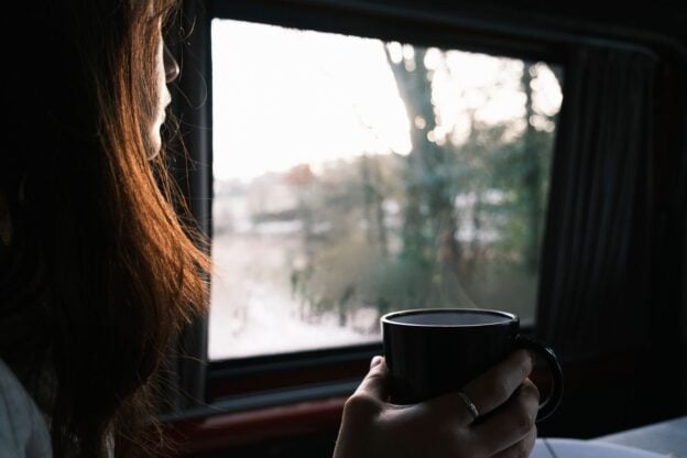 A person alone with a coffee by a window