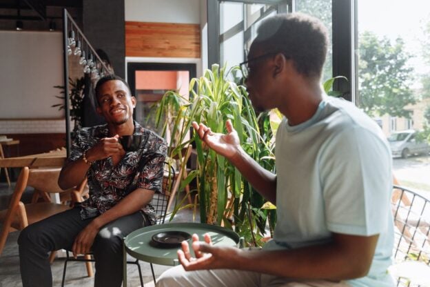 A representative image of two friends talking over coffee, not a photograph of any person discussed in the article.