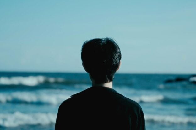 A person standing by the ocean, looking out at the waves