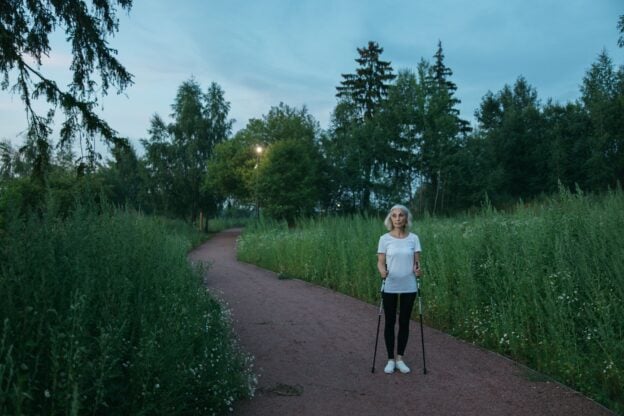 A senior woman exercising with Nordic walking poles in a green park, a representative image and not a photograph of any person discussed in the article.
